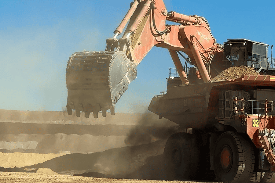 Brisbane sit-on mine dump truck at a construction site, large industrial heavy-duty machinery, used in excavation and mining operations, under clear blue sky.