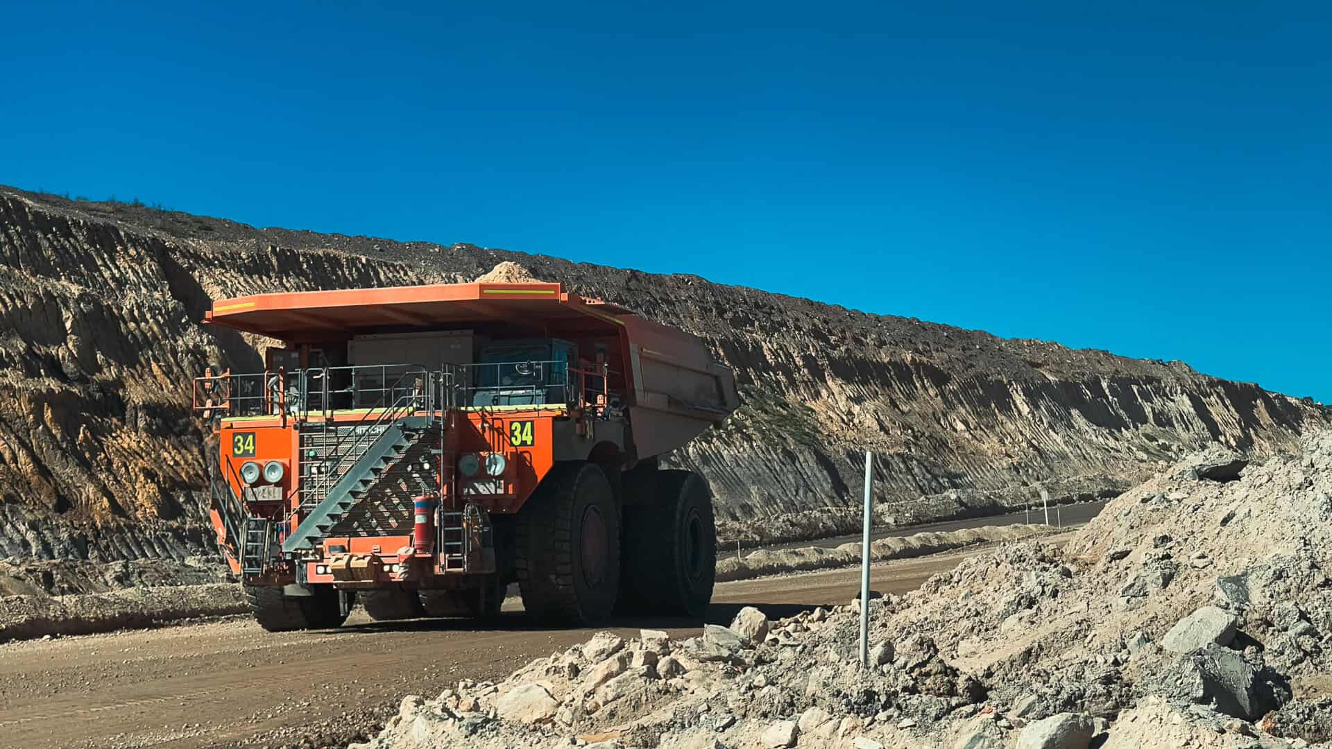 Brisbane sit-on mine dump truck at a construction site, large industrial heavy-duty machinery, used in excavation and mining operations, under clear blue sky.