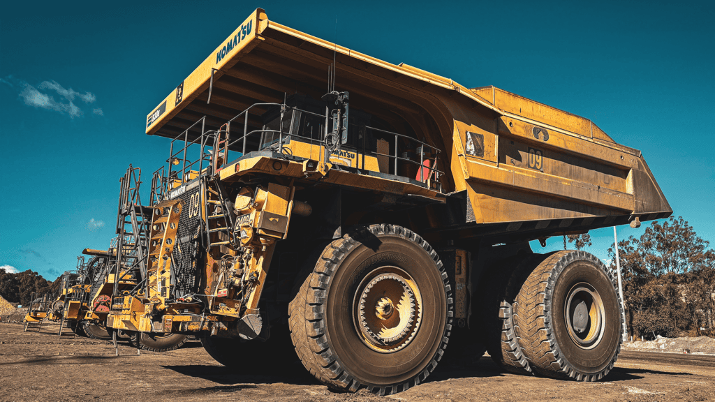 Brisbane sit-on mine dump truck at a construction site, large industrial heavy-duty machinery, used in excavation and mining operations, under clear blue sky.