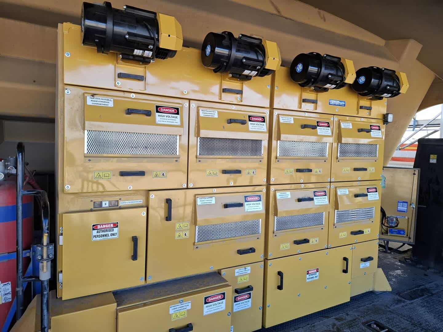 High voltage electrical safety equipment in industrial setting, featuring yellow control panels with warning labels and black electrical components.