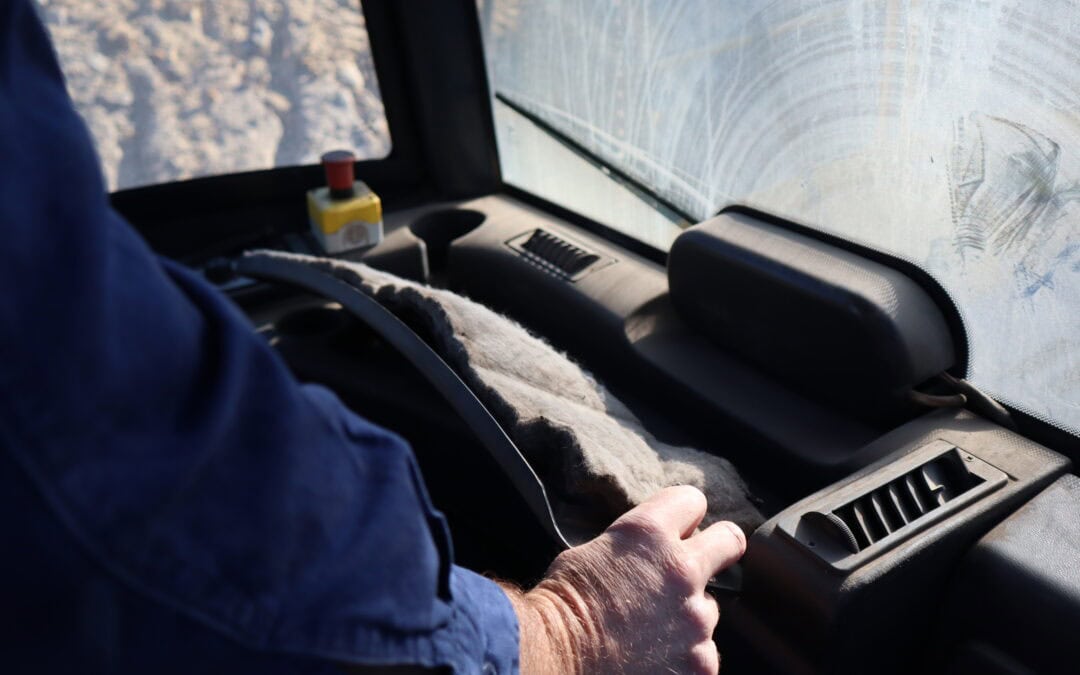 Close-up of a person operating vehicle controls with a focus on air quality monitoring device on the dashboard, highlighting BreatheSafe's air quality solutions for safe driving.