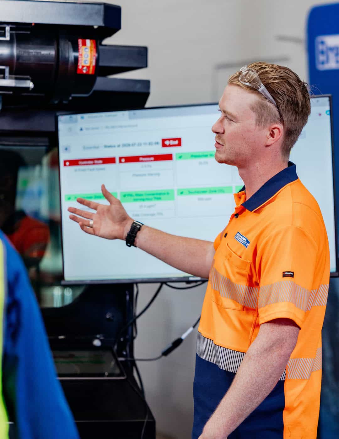 Personal protective equipment (PPE) safety officer in high-visibility uniform discussing safety protocols in industrial environment.